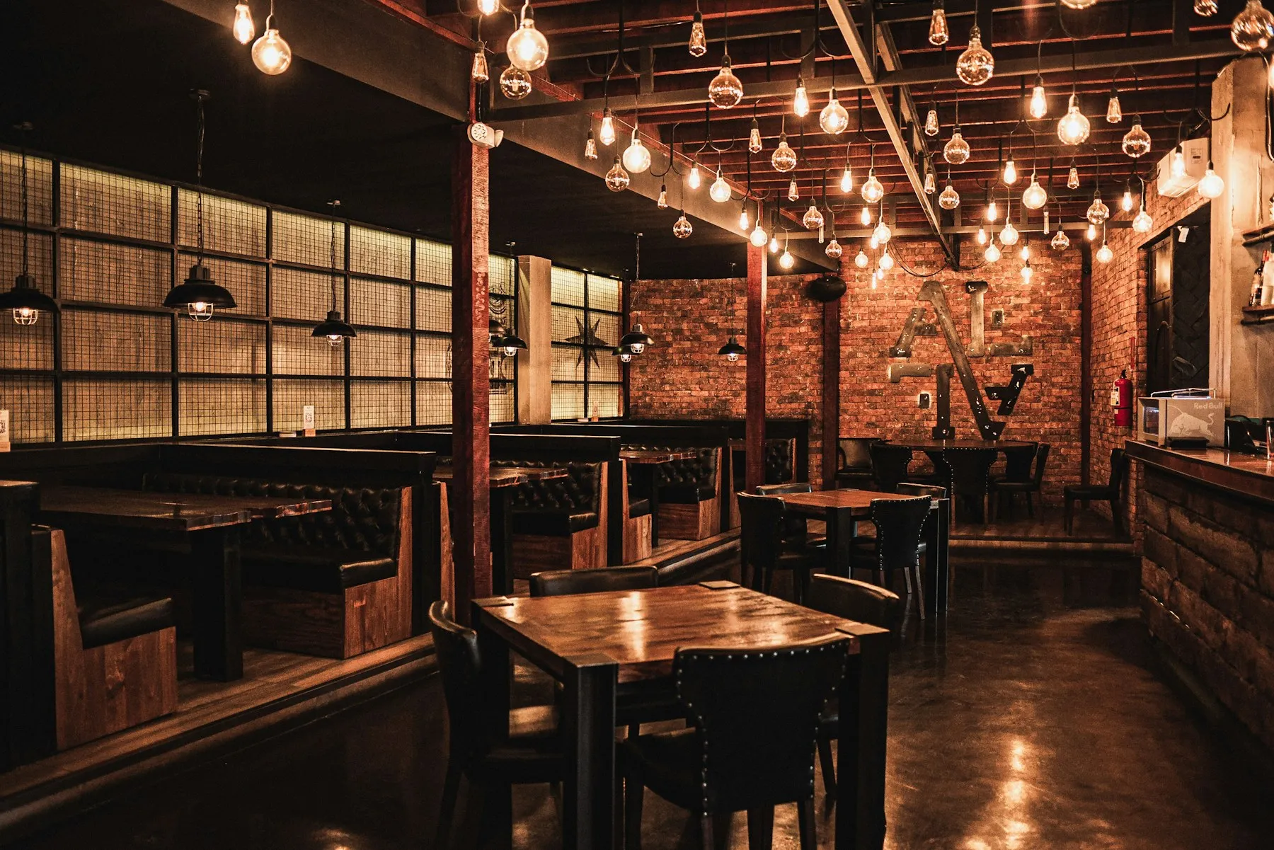 The dining room at night: wooden booths, exposed brick and strings of bare bulbs