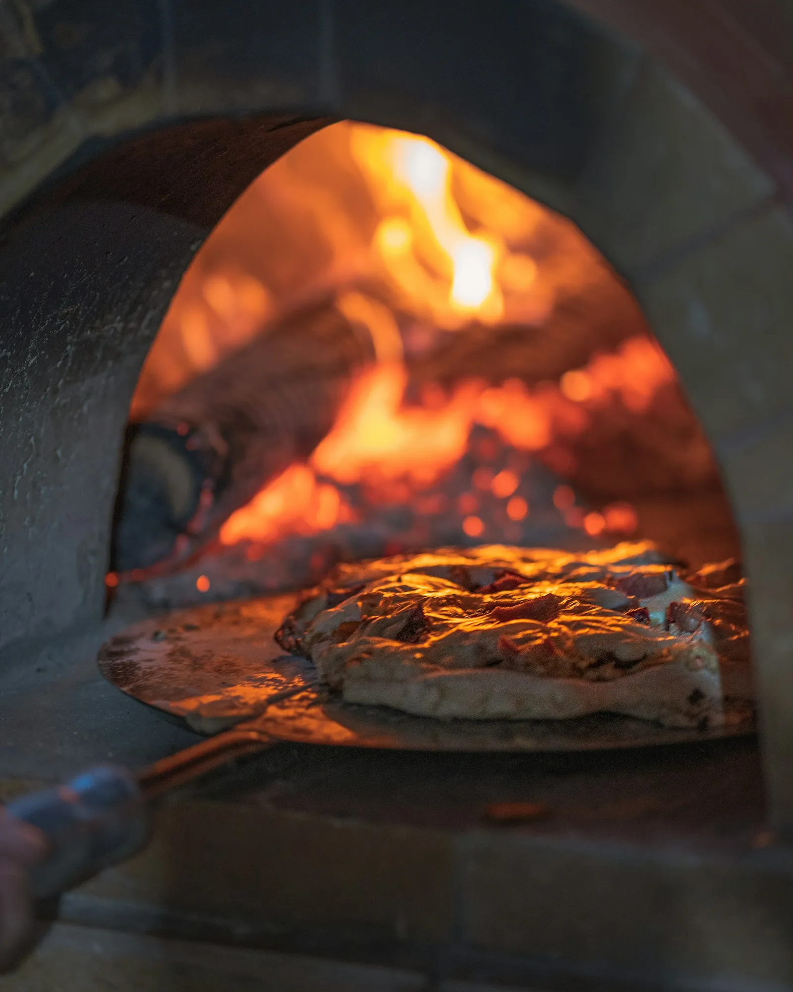 Bread on a long-handled peel, coming out of the wood-fired oven
